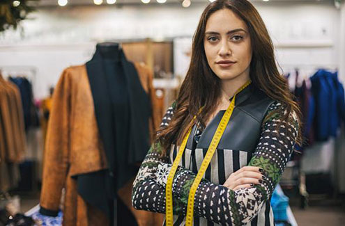 a designer in a studio with clothes behind them