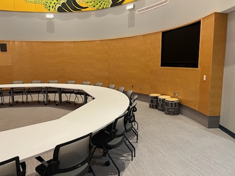 A circled table with chairs and drums on the floor.