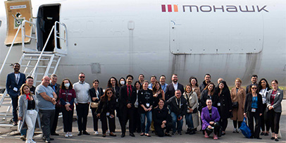 Stiudent nad faculty in front of commercial airplane