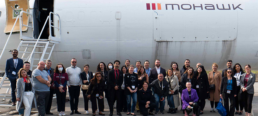 Studfent and faculty gathered in front of a commercial airplane