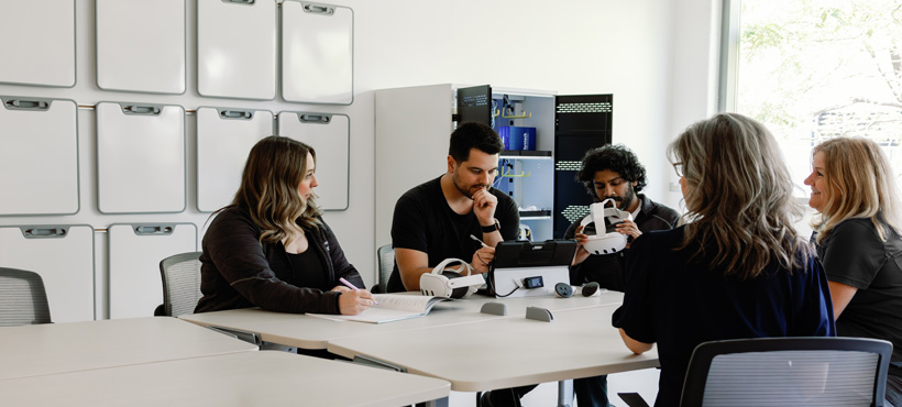 One side of Sim Flex space with Simulation Team seated at tables, reviewing virtual reality equipment