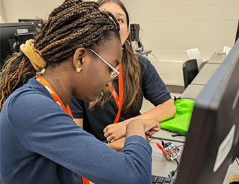 two students working togther on electronics at an event