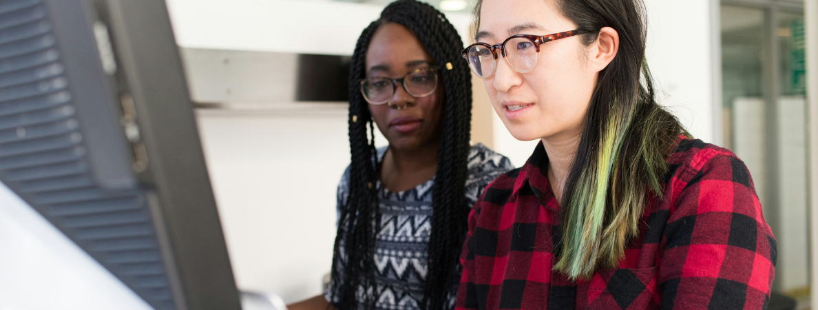 An asian woman and a black woman working together on a computer
