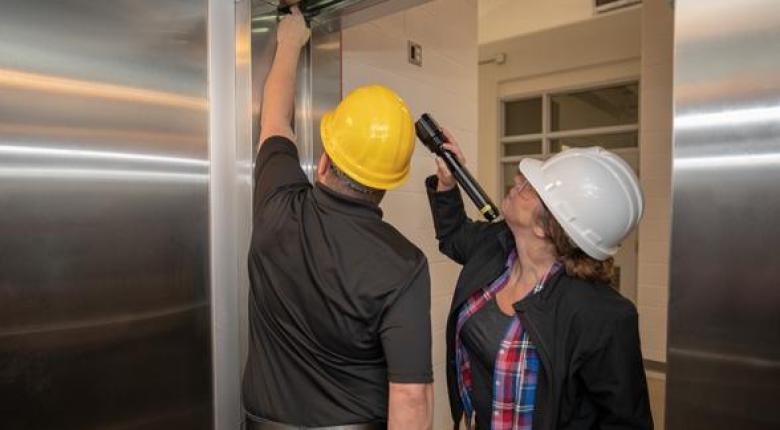 Two people working in an elevator shaft