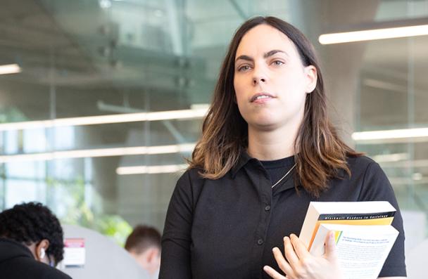 Lauren holding books walking in Mohawk College library