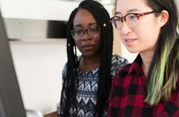 An asian woman and a black woman working together on a computer