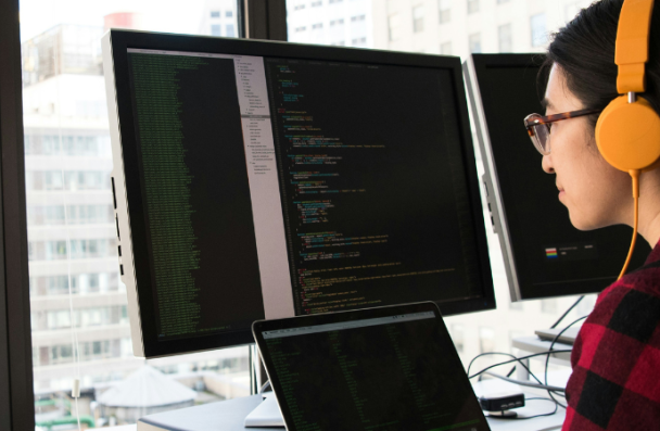 An image of a person working at a computer wearing headphones