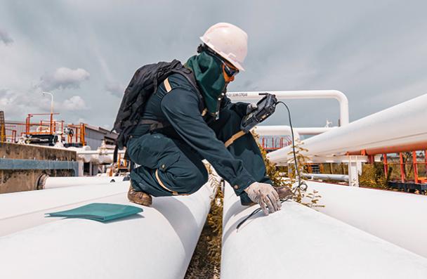 A technician using a sensor to evaluate a pipe.