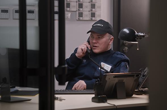 Security officer in uniform at desk answering phone