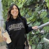 Smiling woman in Mohawk sweater ascending college stairs